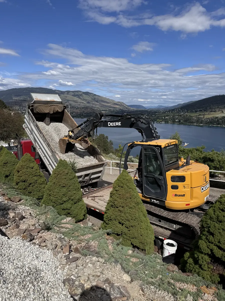 Excavator and dump truck placing material on a steep lake property
